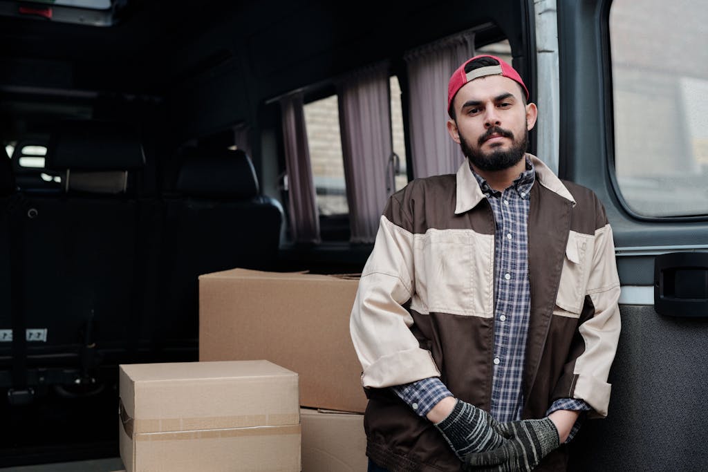 Man in Jacket and with Beard Standing with Boxes behind