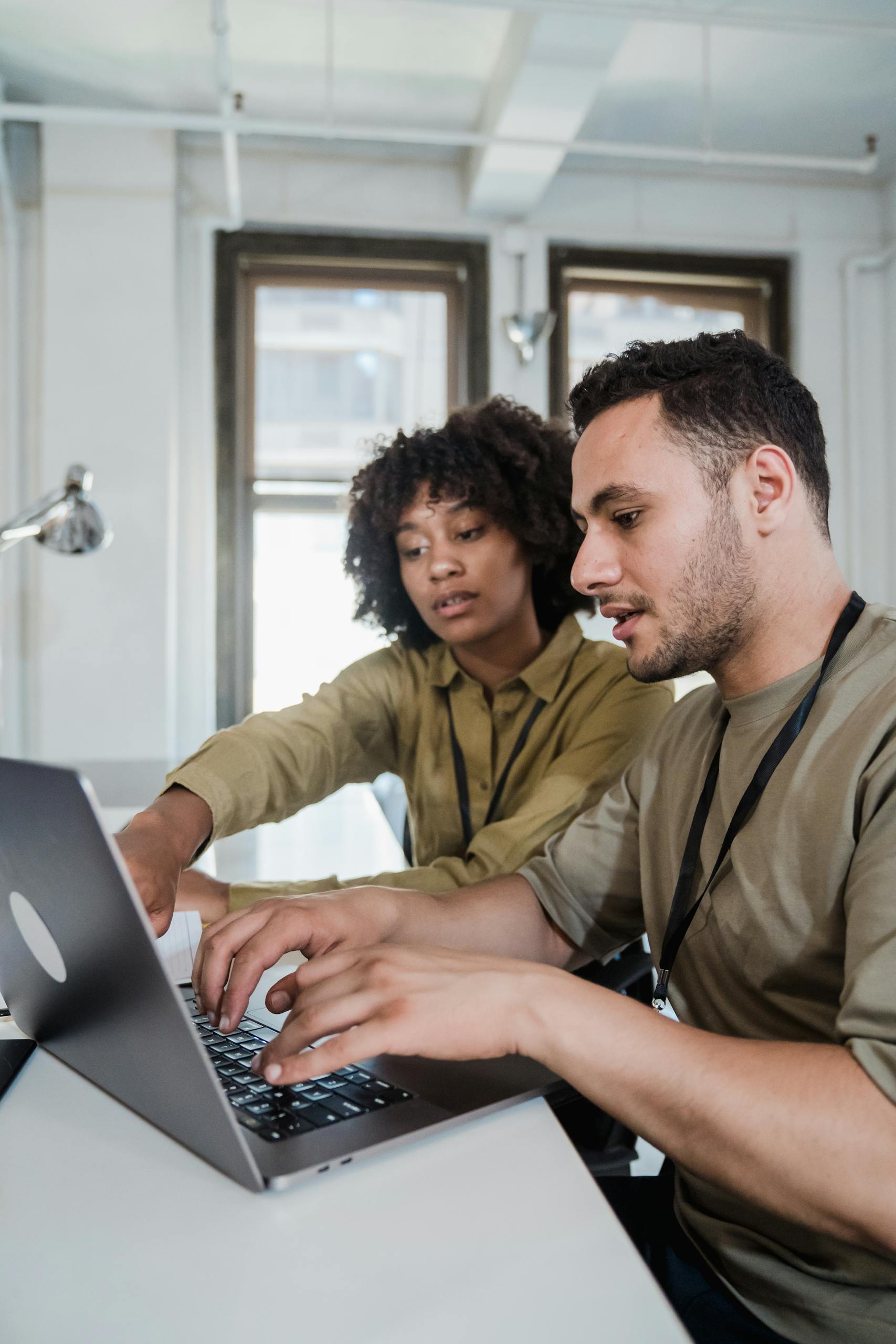 Two professionals collaborating on a project using a laptop in a modern office.