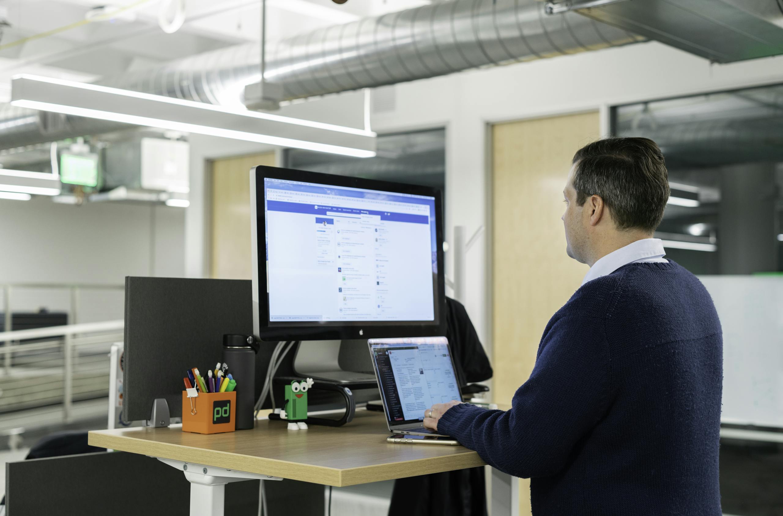 Man working at standing desk on laptop in a modern office setting, focusing on LinkedIn sales tools.