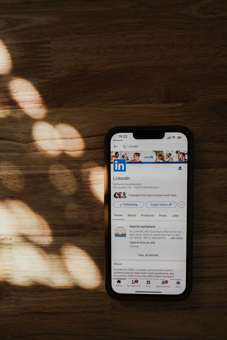 Smartphone on a wooden table showing LinkedIn app in natural light.